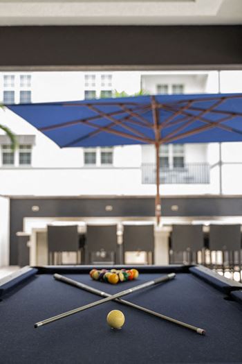 A billiards table in a room with an umbrella